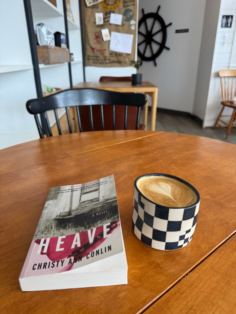 A book and latte on a table in a coffee shop